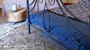 Een tent met twee bedden, waarvan één met een blauwe matras en de ander met een bloemenprint beddekleed.