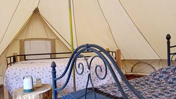 Une tente équipée de deux lits, l’un avec un matelas bleu et l’autre avec une couverture à motifs floraux.