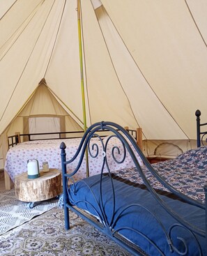Une tente équipée de deux lits, l’un avec un matelas bleu et l’autre avec une couverture à motifs floraux.