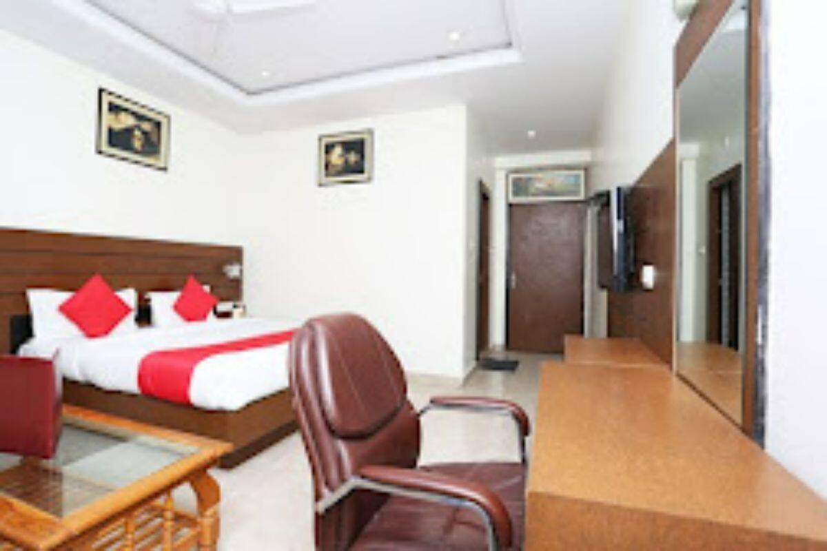 Habitación de hotel con cama, escritorio, silla y espejo.