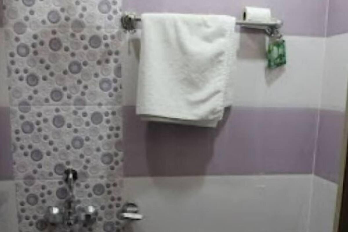 Un baño con inodoro, un cubo rojo, toallero y cortina de ducha con diseño circular.