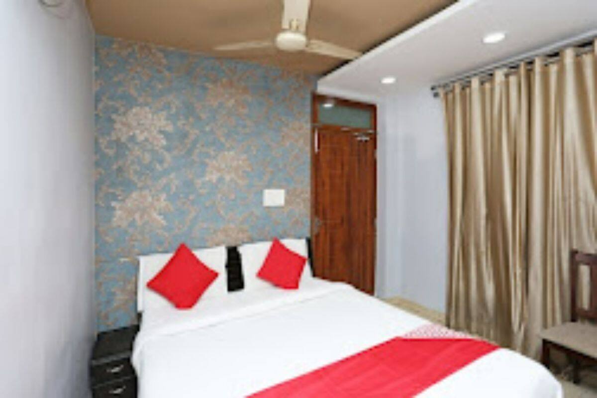 Un dormitorio con cama, ventilador de techo, puerta de madera y ventana con cortinas.