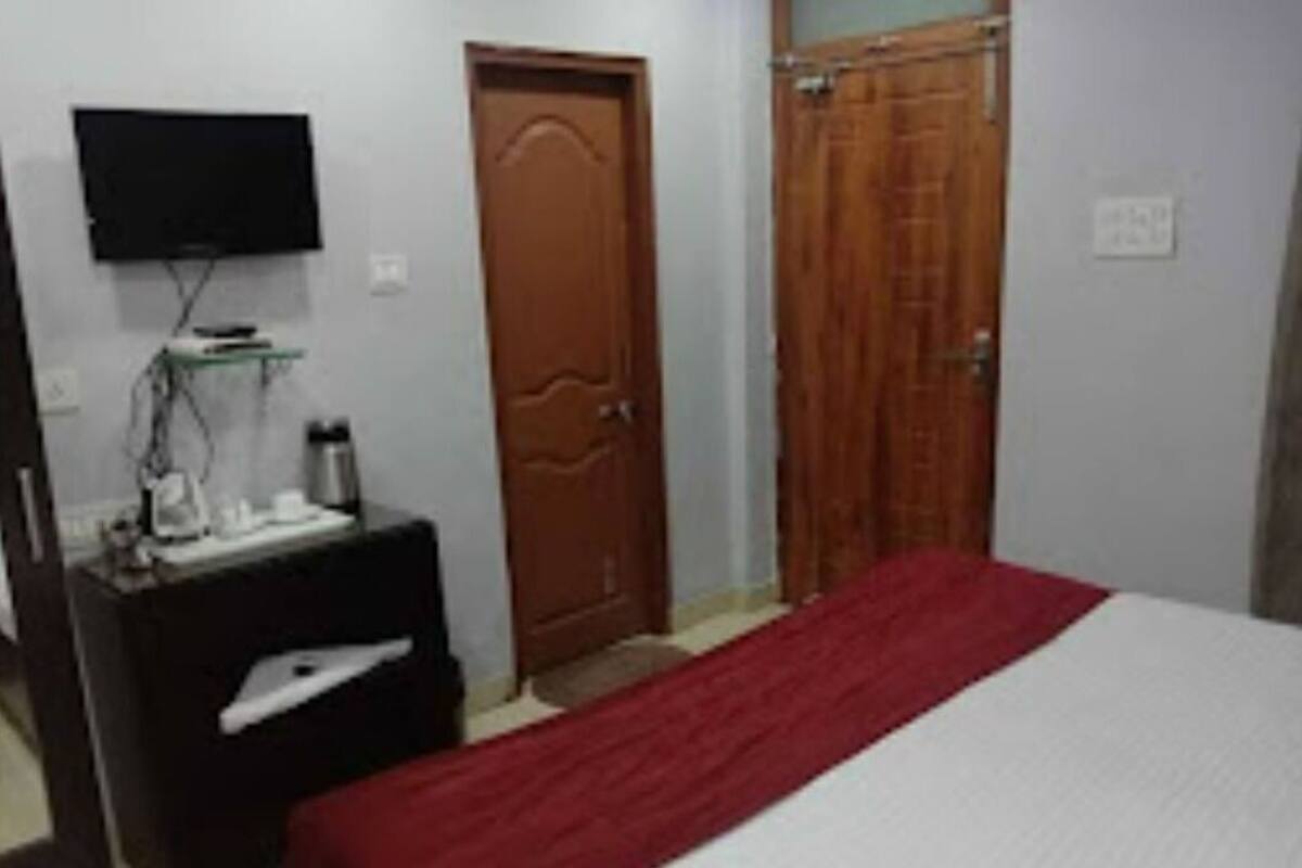 Un dormitorio con cama, televisión en la pared, puerta de madera y armario.