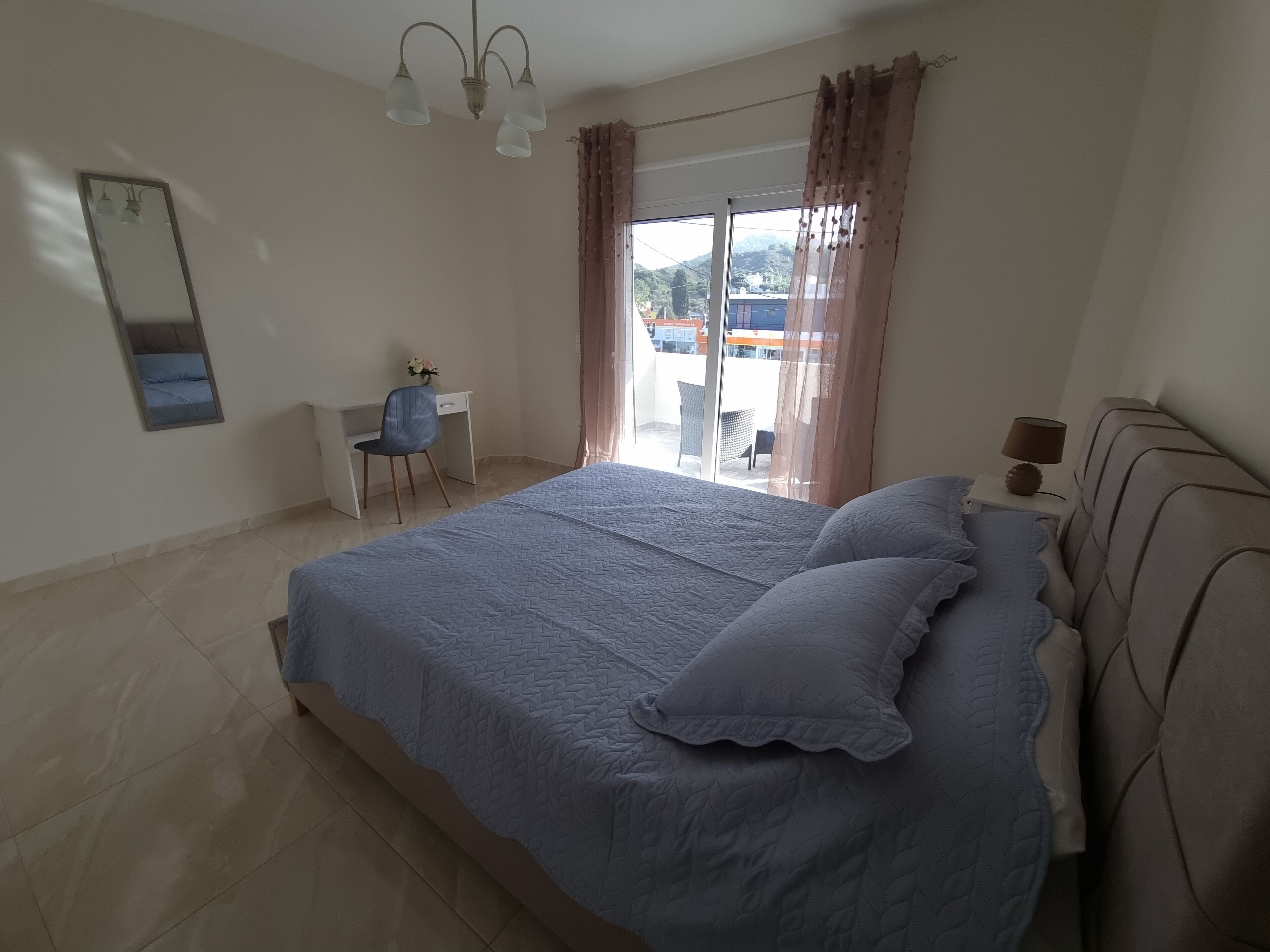 A bedroom with a large bed, a desk, and a chair.