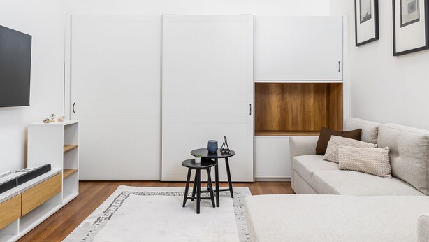 Una sala de estar moderna con un sofá, una mesa de centro, un televisor y una lámpara de techo.
