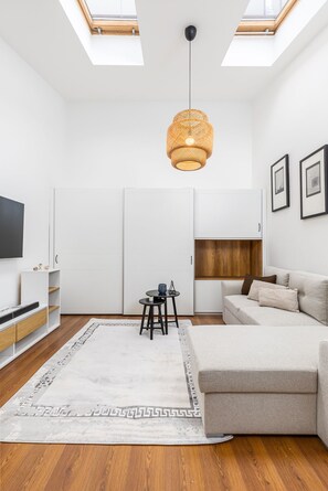 A modern living room with a sofa, a coffee table, a TV, and a ceiling light. - Venus Apartments - Opera II (Budapest)