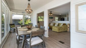 Un espace repas comprenant une table et des chaises en bois, un lustre et une vue sur l’extérieur.