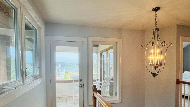 A staircase with a wooden handrail, a white door leading to a balcony, and a chandelier.