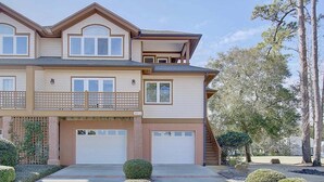 A two-story house with a garage, a balcony, and a well-maintained lawn.