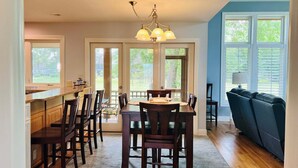A kitchen with a dining table, chairs, a chandelier, and a view through the windows.