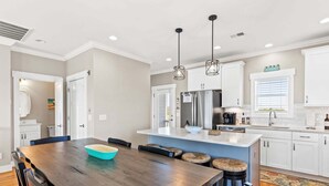 A modern kitchen with white cabinets, a central island, and pendant lighting.