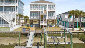 A beachfront property with a two-story building, a wooden deck, and a small boat dock.