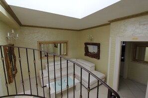 A staircase with a white cushioned bench, a chandelier, and a framed painting on the wall. - DIO DEL MARE LUXURY ROOM (Porto Cesareo)