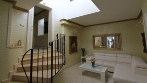 Ein Wohnzimmer mit Treppe, einem weißen Sofa, einem Couchtisch, einem Gemälde und einem Spiegel.