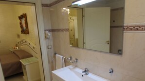 Ein Badezimmer mit weißem Waschbecken, Spiegel und gefliesten Wänden.
