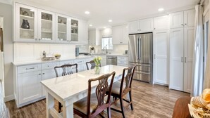 A modern kitchen with white cabinetry, a marble island, and stainless steel appliances. - 90 Walk Score, Steps to Beach, Dining (Carlsbad)