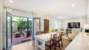 A spacious living area with a dining table, chairs, and a TV. - 90 Walk Score, Steps to Beach, Dining (Carlsbad)