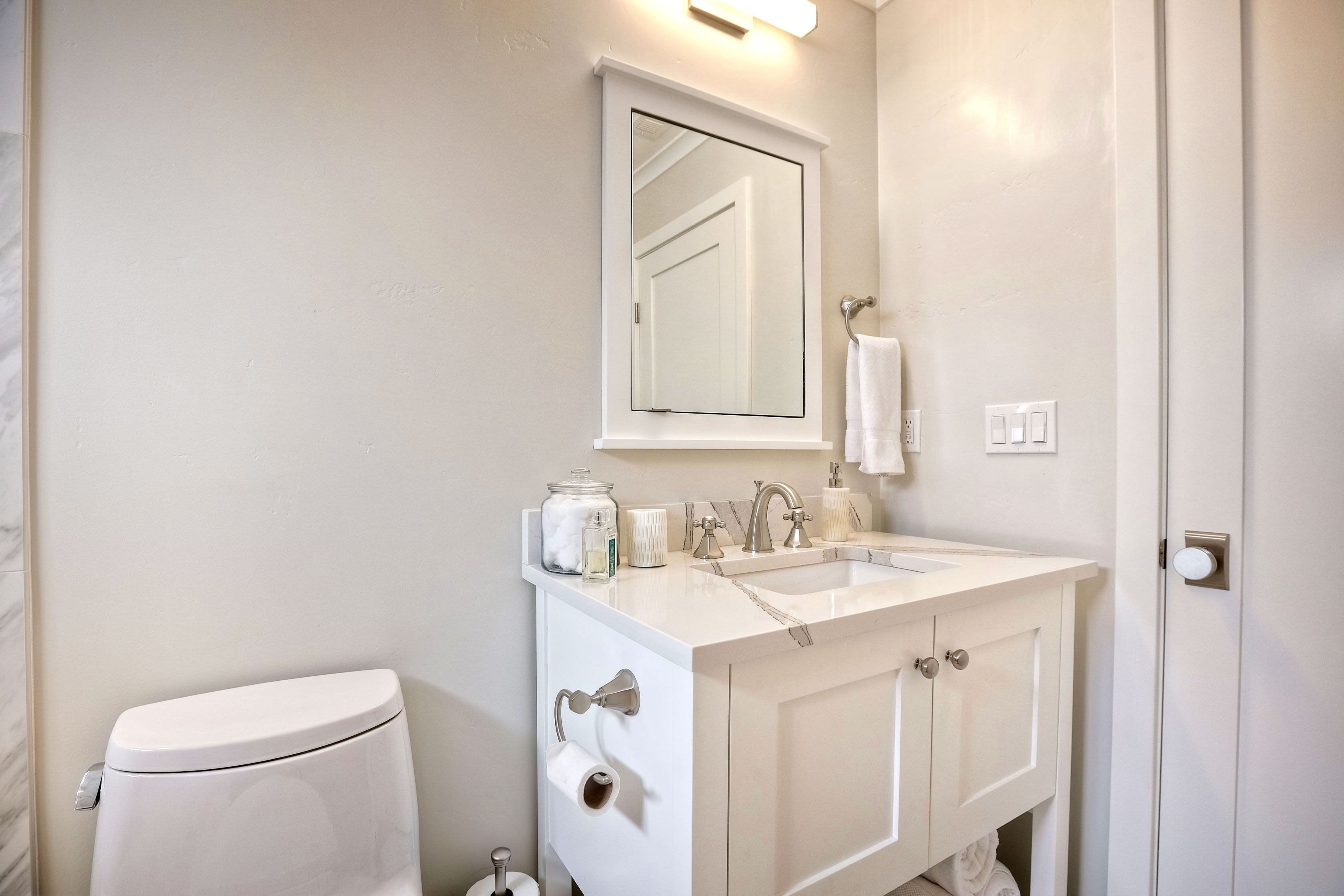 Een badkamer met toilet, wastafel, spiegel en kastjes.
