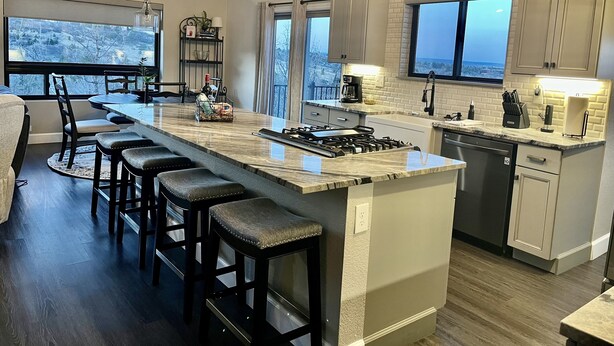 Een moderne keuken met een groot eiland, barstoelen, een eethoek en uitzicht op de omgeving.