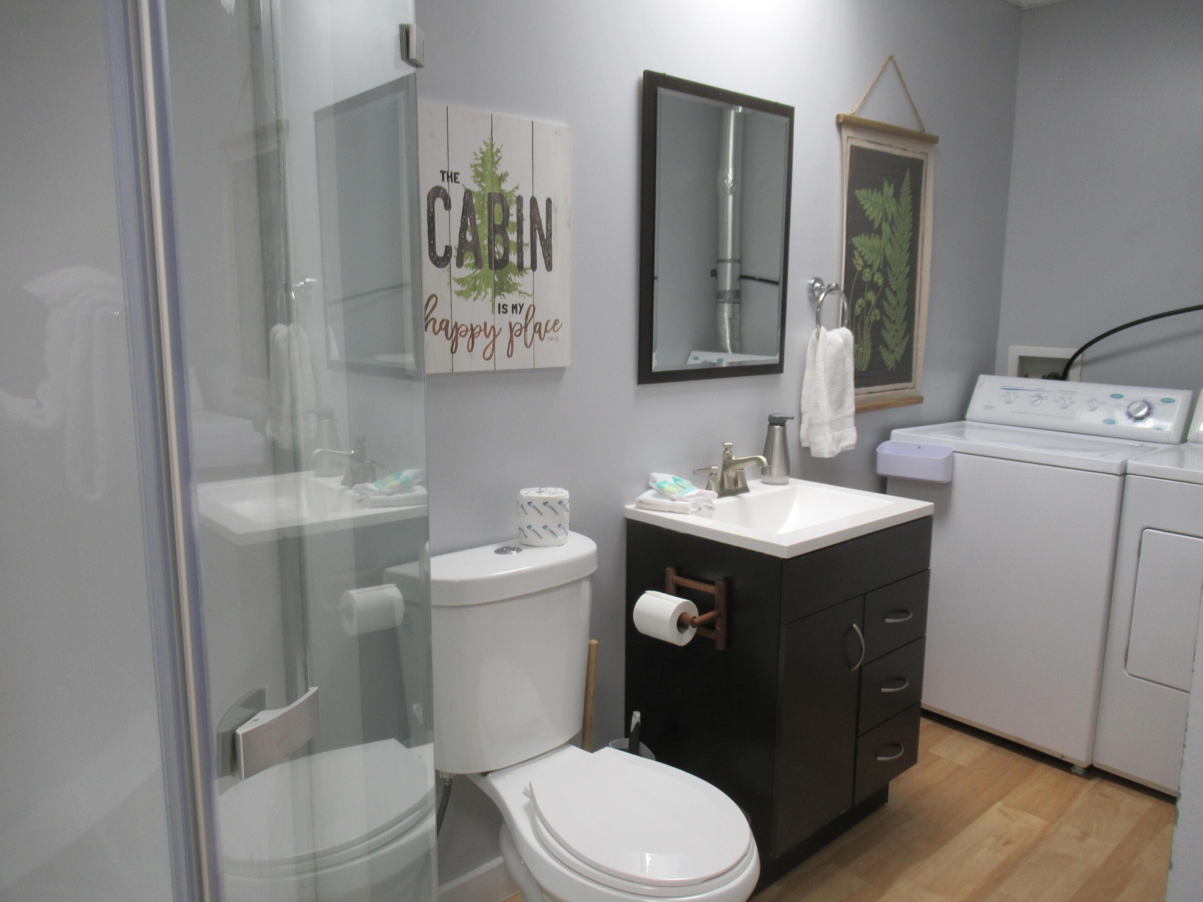 Une salle de bain équipée de toilettes, d’un lavabo, d’un miroir et d’un lave-linge.