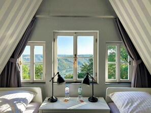 A room with two beds, a table with two lamps, and a view of a landscape through large windows. - Holiday Home Mister Stringer in Altes Forsthaus Boppard (Boppard)