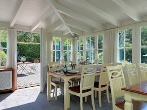 A dining area with a table set for six, surrounded by white chairs, under a white ceiling with exposed beams. - Holiday Home Mister Stringer in Altes Forsthaus Boppard (Boppard)