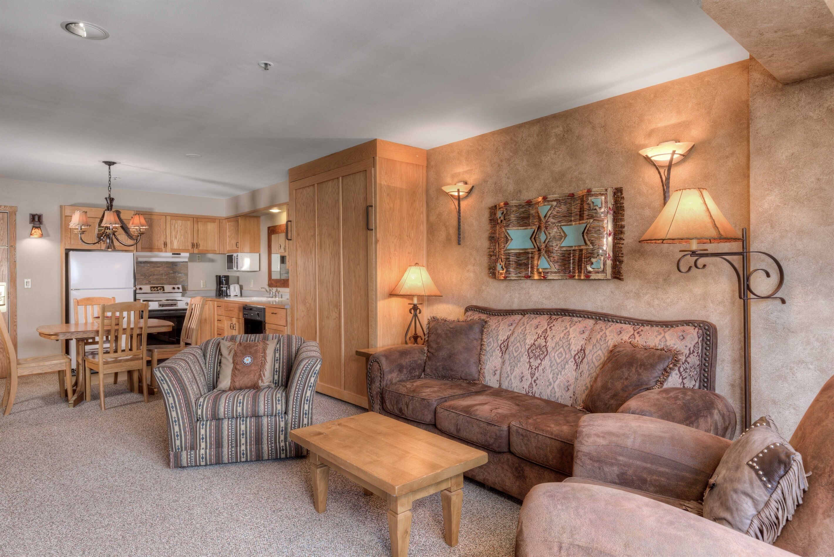 A cozy living room with a sofa, a patterned armchair, a wooden coffee table, and a dining area with chairs and a table.