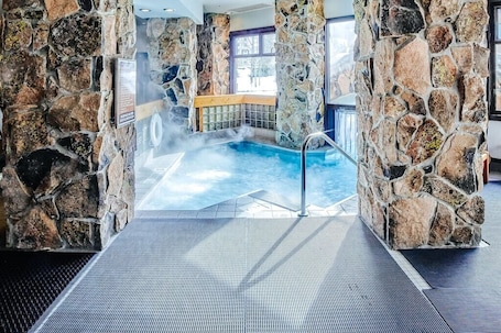 A stone-walled indoor pool with a clear view of the outdoors through a window.