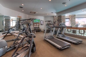 A gym with treadmills, elliptical machines, and free weights.