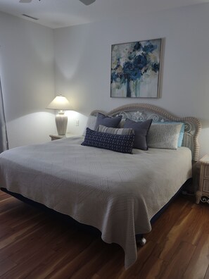 Relax in a stylish bedroom with a large bed, wicker headboard, and a wall-mounted painting.