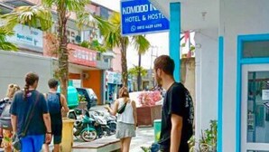 A hotel entrance with a signboard, outdoor seating area, and potted plants. - Komodo Indah Hotel (Labuan Bajo)
