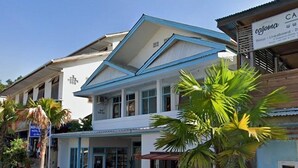 A two-story building with a blue and white facade, a visible ground floor entrance, and a parked car in front. - Komodo Indah Hotel (Labuan Bajo)