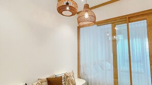 Een moderne woonkamer met een houten bank, een bank met gestreepte kussens en een groot raam met dunne gordijnen.