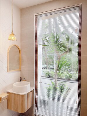 A modern bathroom with a white sink, wooden vanity, and a large window with blinds. - Baphu Apartment-5min walk to MyKhe beach (Da Nang)