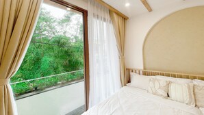 Een slaapkamer met een groot bed, een raam met gordijnen en uitzicht op groen buiten.