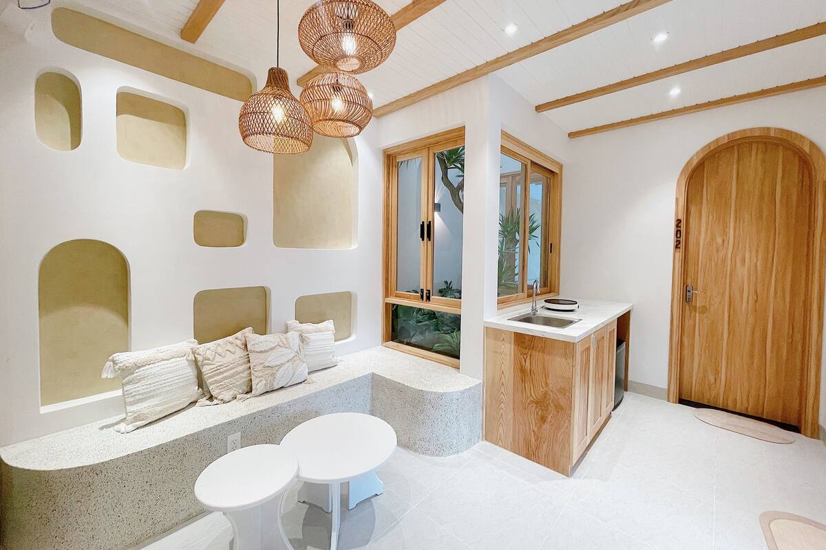 Un intérieur moderne avec un banc intégré, un petit coin cuisine et une porte en bois.