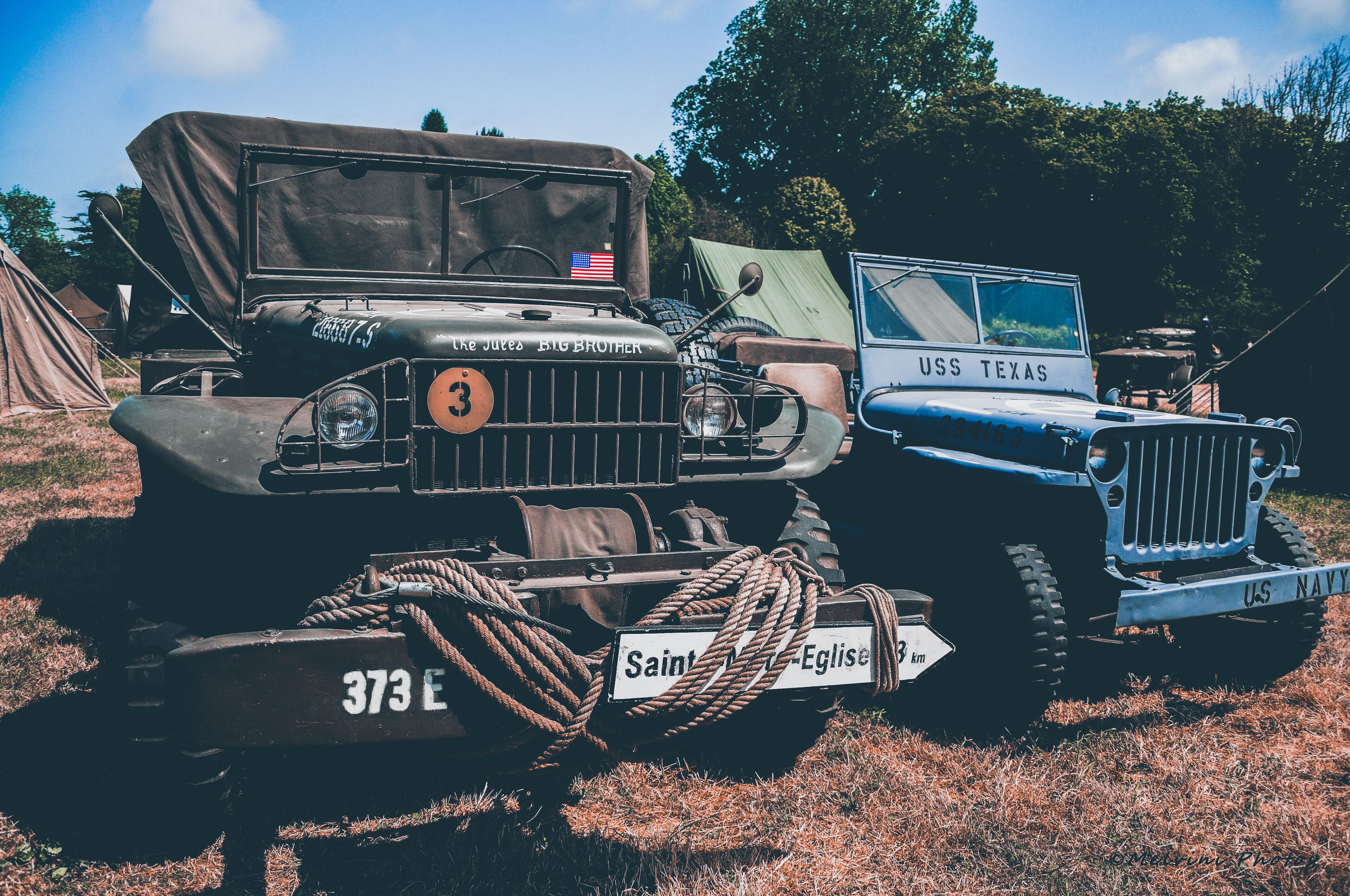 Two vintage military jeeps, one labeled "USS TEXAS" and the other "Saints & Elders."