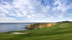 En golfbana vid kusten med fri utsikt över havet och en klippig brant.