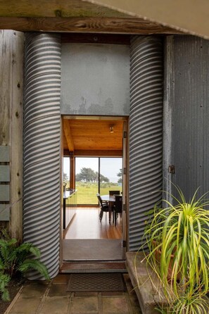 Una entrada moderna con techo de madera y vista a un área de comedor al aire libre.