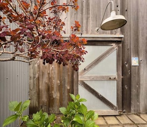 Een houten poort met een metalen deur, een hangende lamp en een plant op de voorgrond.