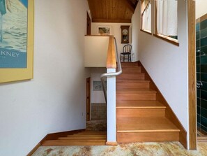 A wooden staircase with a white handrail leading to a landing.