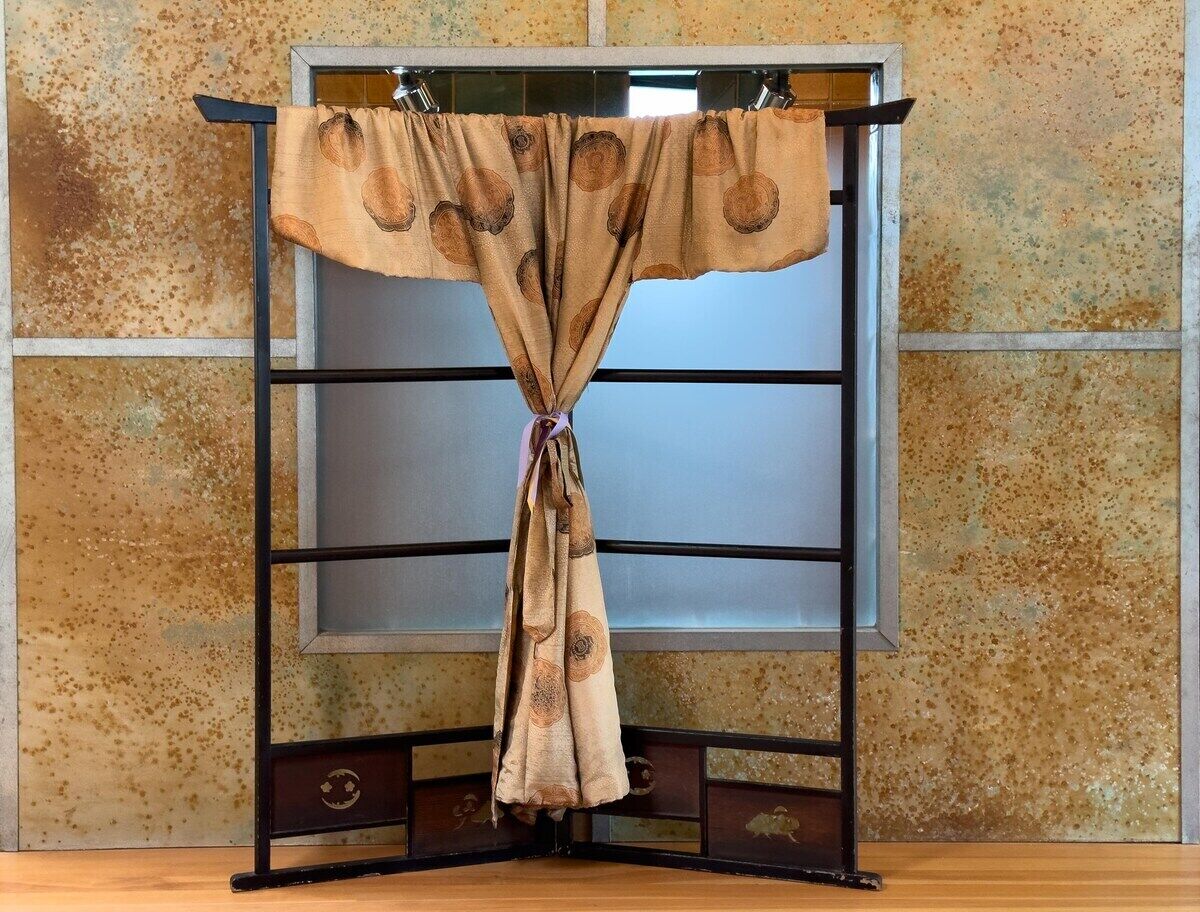 A curtain on a metal stand with a textured wall in the background.