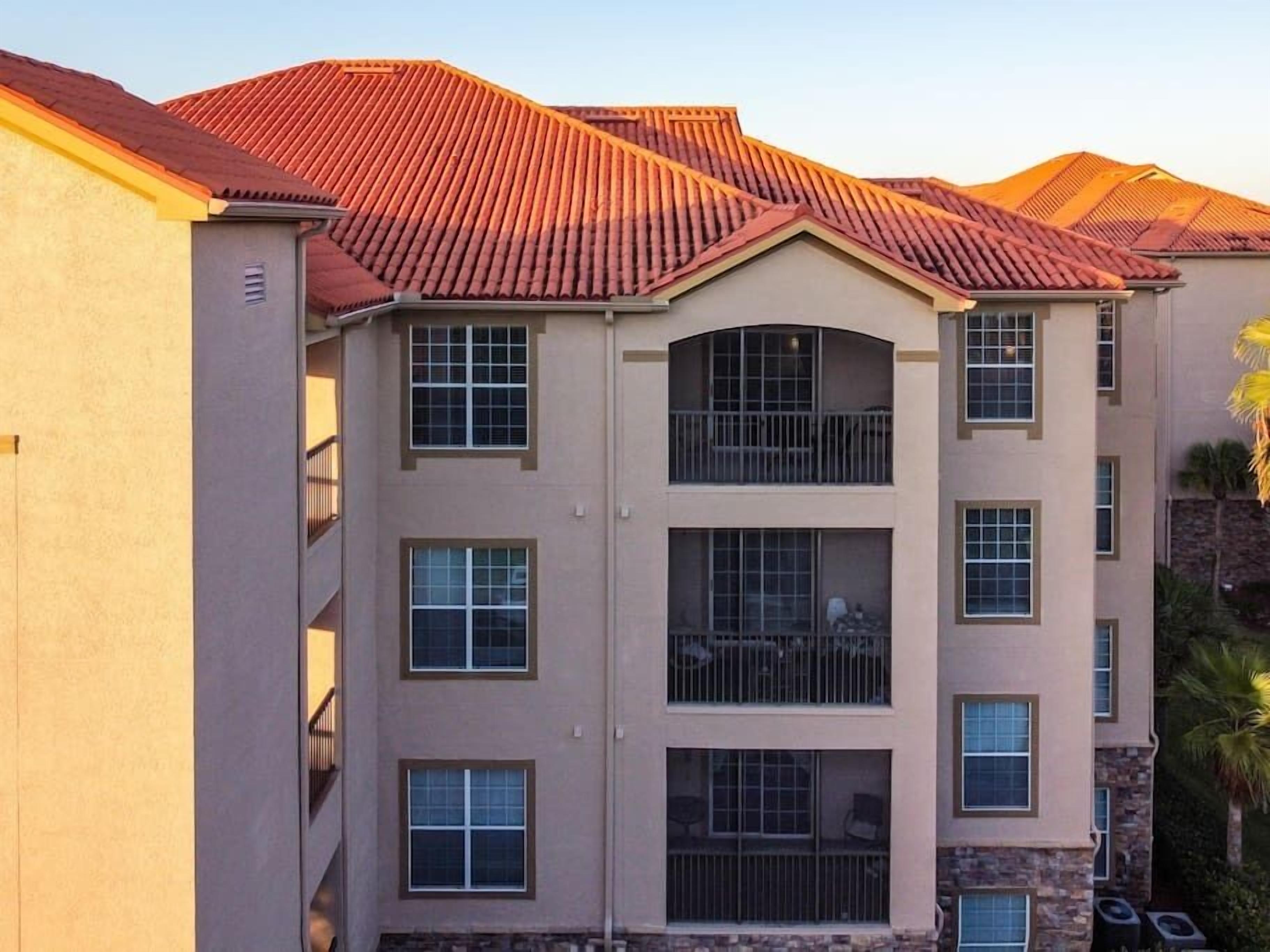 A multi-story building with a beige facade, red-tiled roof, and multiple balconies.