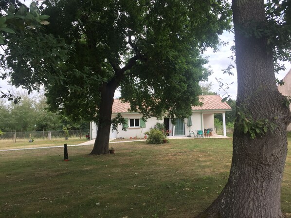 Ein Haus mit rotem Ziegeldach, einer Veranda und einem Rasen.