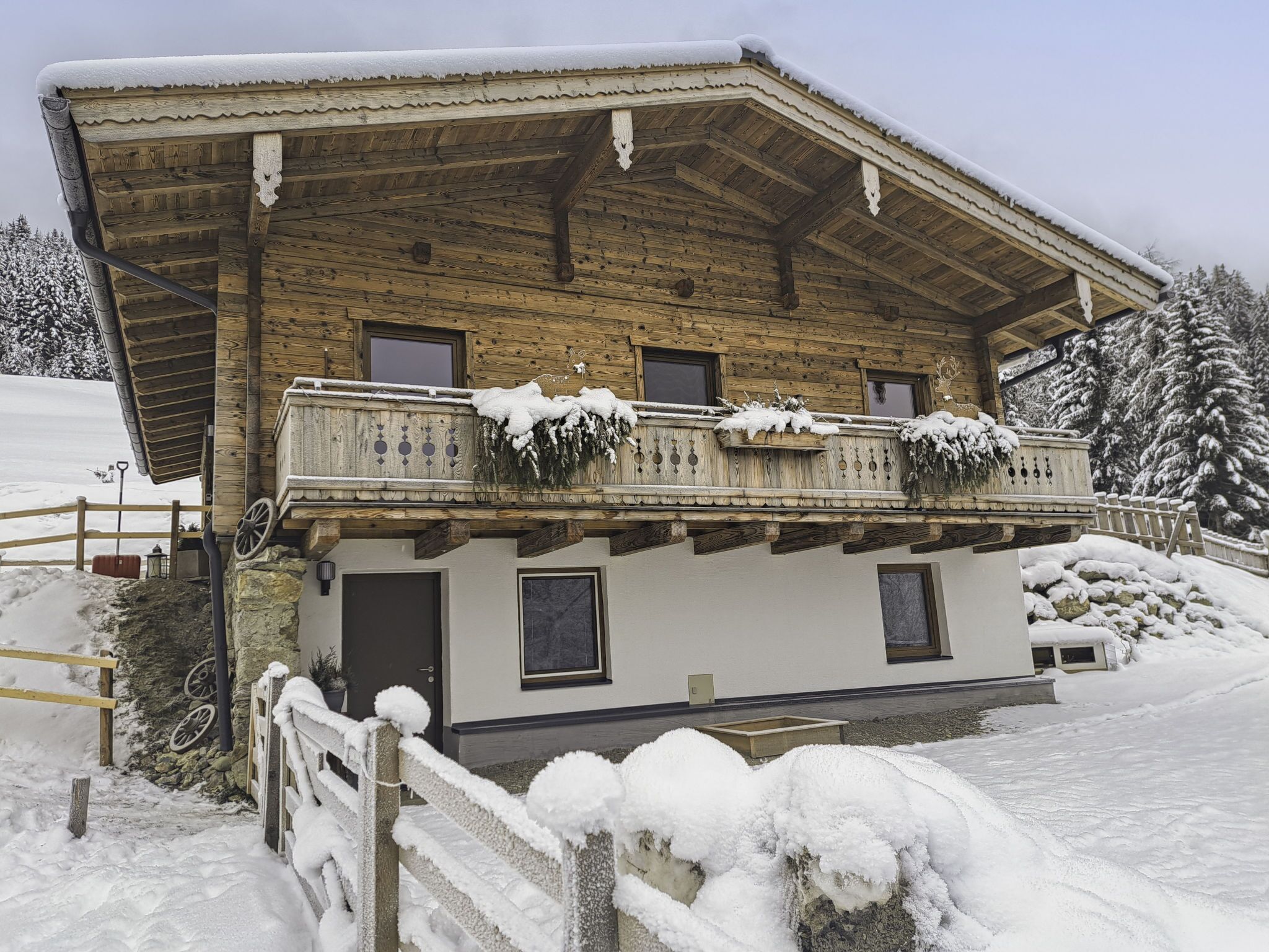Ein traditionelles Holzhäuschen mit Balkon, vor einer verschneiten Landschaft gelegen.