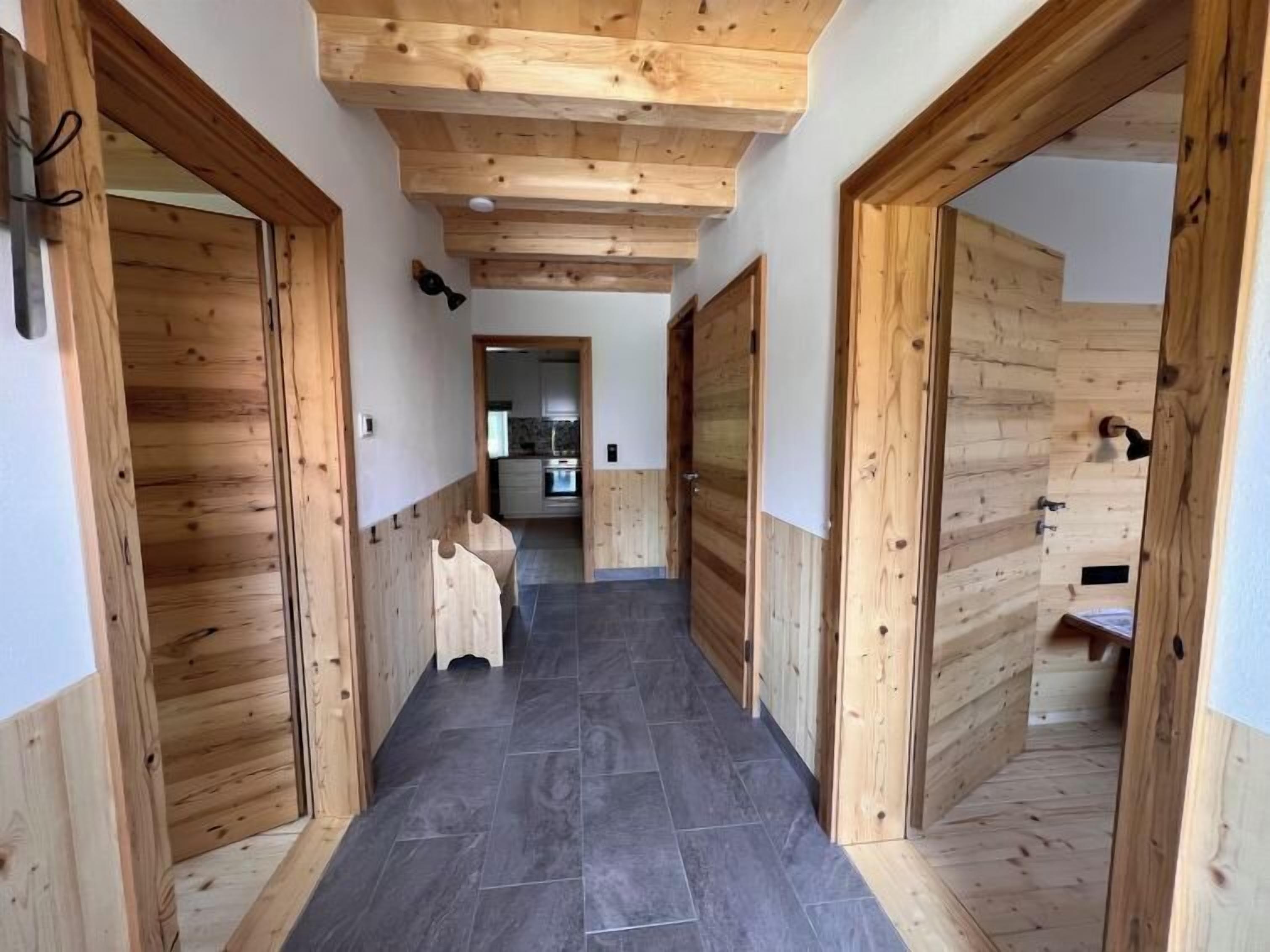 Un couloir aux murs et au plafond en bois, qui mène à une cuisine.