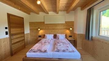 Ein Schlafzimmer mit Holzvertäfelung, einem großen Bett, zwei Nachttischen und einem Fenster mit Vorhängen.