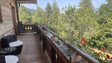 Eine Holzterrasse mit Korbmöbeln, mit Blick auf ein bewaldetes Gebiet.
