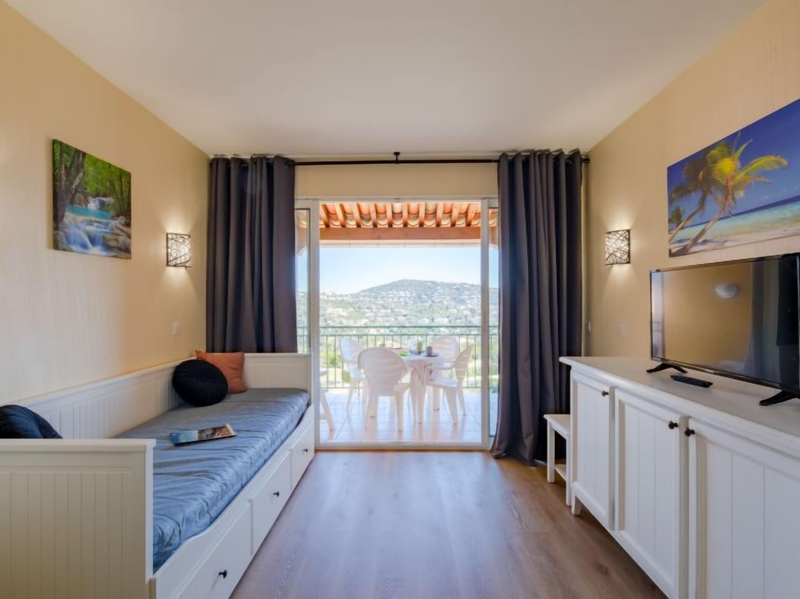 Ein kleines Zimmer mit Bett, Fernseher und Balkon mit Aussicht.