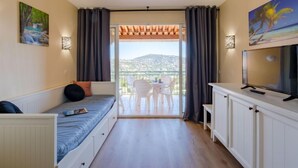 Una camera compatta con un letto, una televisione e un balcone con vista.